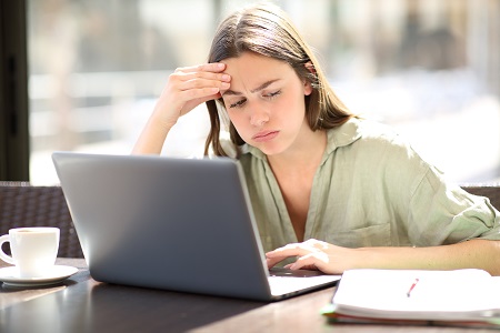 Das Bild zeigt eine Studentin, die verzweifelt an ihrem Laptop sitzt.