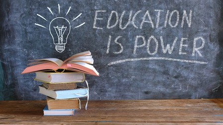 Das Bild zeigt einen Stapel Bücher und eine Tafel auf der eine Glühbirne und "Education is power" gemalt worden ist.