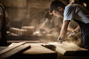Das Bild zeigt einen Mann, der Holz verarbeitet.
